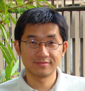 A photograph of a man with black hair and glasses